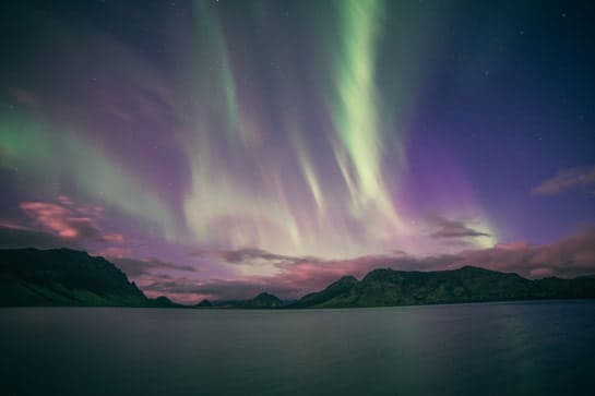 Northern Lights in purple sky over the water at night
